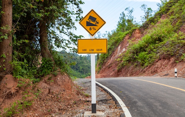 Foto use sinal de marcha baixa, sinais de alerta de tráfego rodoviário na curva da estrada e inclinação