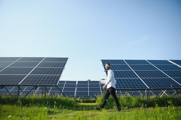 Usina de energia solar de trabalhador masculino em um fundo de painéis fotovoltaicos