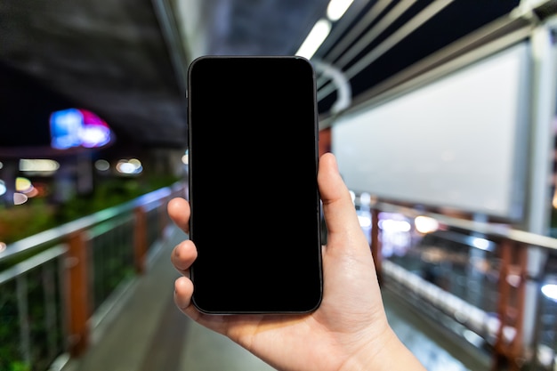 Uso femenino mano smartphone con pantalla negra vacía en el Skywalk en Bangkok