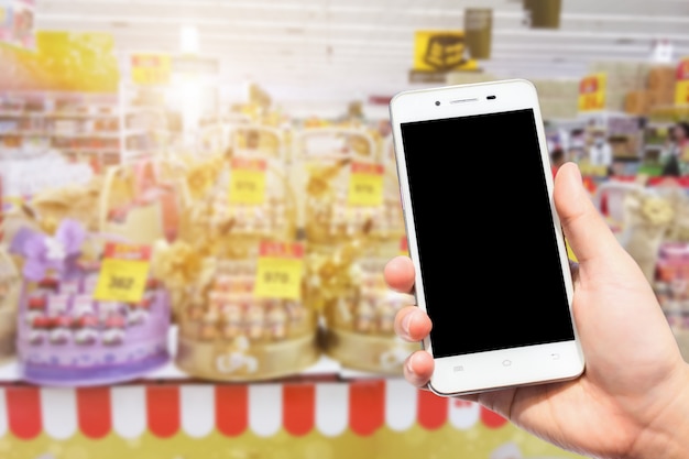 Foto el uso femenino sostiene imágenes borrosas de teléfonos inteligentes del nido de muchas aves comestibles y cestas de regalo de bebidas saludables para la venta en el supermercado