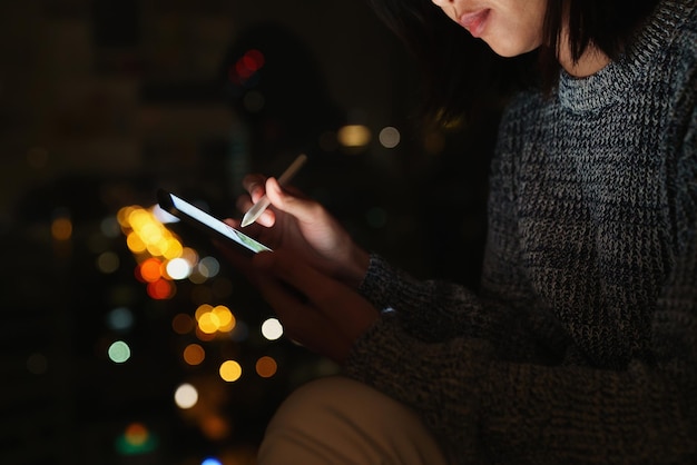 Uso de lápiz óptico en tableta digital en el estilo de vida nocturno por la noche en la ciudad