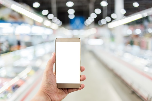 uso de la mano teléfono inteligente con desenfoque de fondo del supermercado