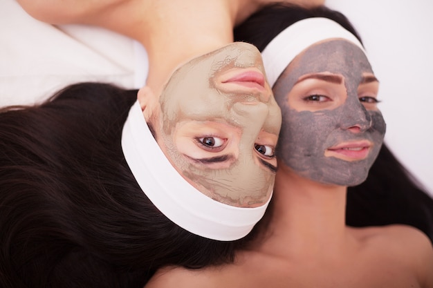 Uso de una mascarilla facial para dos mujeres jóvenes en un salón de belleza.