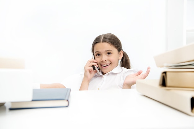 Uso de nuevas tecnologías de comunicación en la educación escolar Niña pequeña hablando por teléfono móvil en la lección Niña pequeña en edad escolar que tiene una llamada telefónica Niña en edad escolar que desarrolla habilidades de comunicación Estar en una llamada