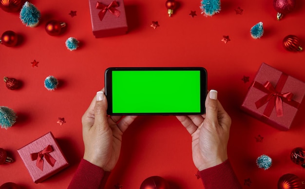 Uso de Smartphone con pantalla verde en blanco en la mesa con adornos navideños Vista superior