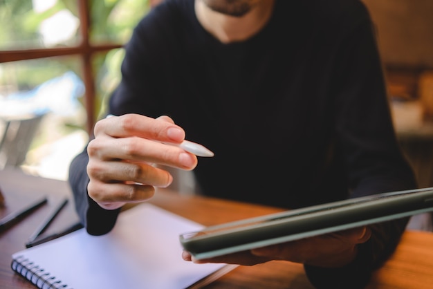 Uso de tecnología de tableta digital profesional para escribir un trabajo comercial, comunicación moderna en el ciberespacio de la pantalla en línea, escritura a mano a través de un bolígrafo blanco, estilo de vida con la misma computadora portátil o portátil usando