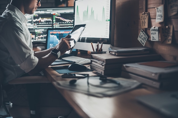 Uso de tecnologías modernas en el trabajo. Primer plano de joven empresario trabajando en tableta digital mientras está sentado en el escritorio en la oficina creativa