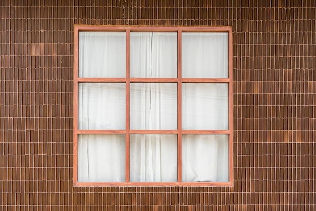 Äußeres der Wandlehmziegel und des hölzernen Fensters mit weißem Vorhang des tropischen Hauses