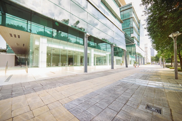 Äußeres eines modernen Bürogebäudes aus Stahl und grünem Glas mit leerem Gehweg. Panorama- und Perspektivansicht. Abstraktes, inspirierendes, künstlerisches und modernes Architektendesign.