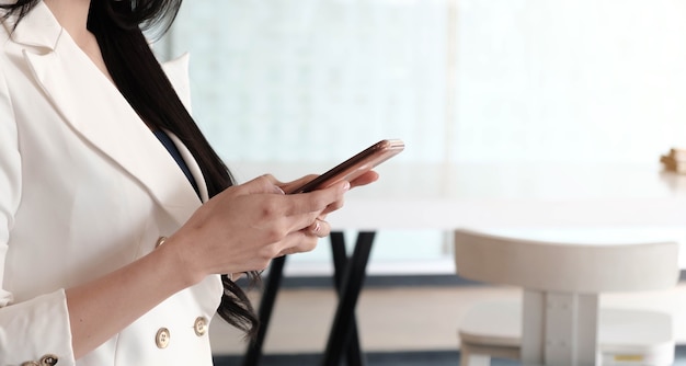 Usuário de mulher segurando um telefone inteligente assistindo vídeo, jogando, fazendo compras, conversando em um aplicativo de tecnologia móvel.