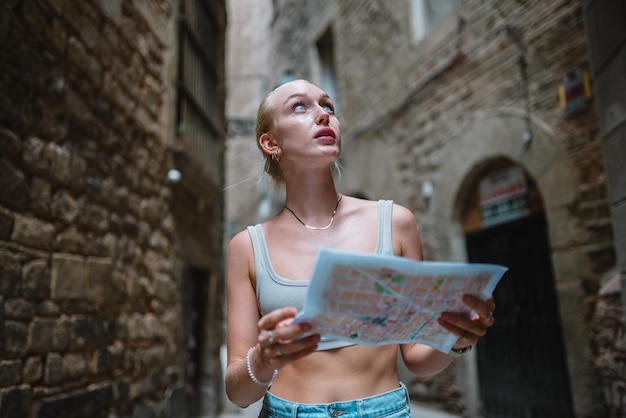 Usuario de mapas turísticos femeninos caminando en el callejón del casco antiguo usando un mapa Barcelona España