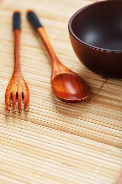 Utensilien aus Holz, Schüssel und Löffel auf einem Schneidebrett auf weißem Hintergrund