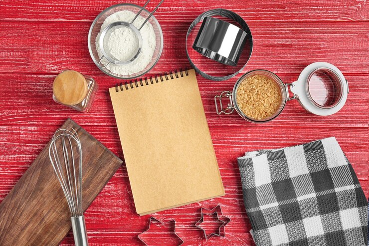 Foto utensilios de cocina con ingredientes para pasteles y cuaderno de notas sobre fondo de madera de color