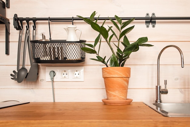 Utensilios de cocina de latón accesorios de chef Cocina colgante con paredes de azulejos blancos y mesa de madera Espacio de copia de fondo de cocina