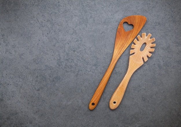 Los utensilios de cocina de madera bordean sobre fondo de piedra oscura.