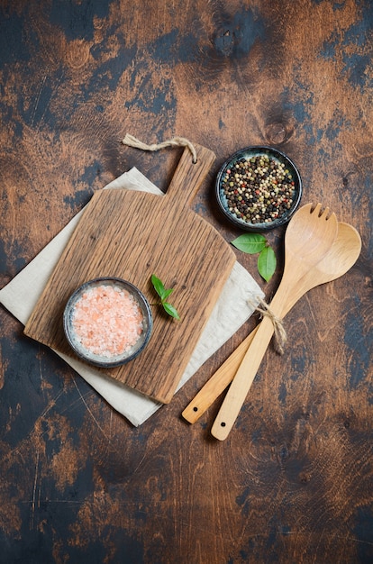 Utensilios de cocina de madera y especias. Cucharas de madera, tabla de cortar, servilleta y especias en una mesa de madera vieja.