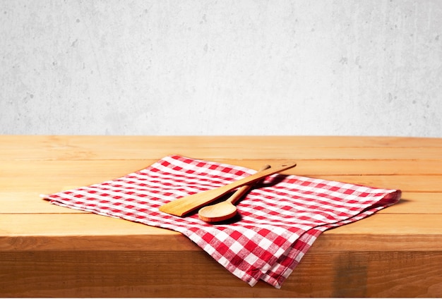 Utensilios de cocina de madera en una servilleta sobre fondo de madera aislado