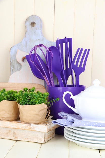 Utensilios de cocina de plástico en taza sobre mesa de madera