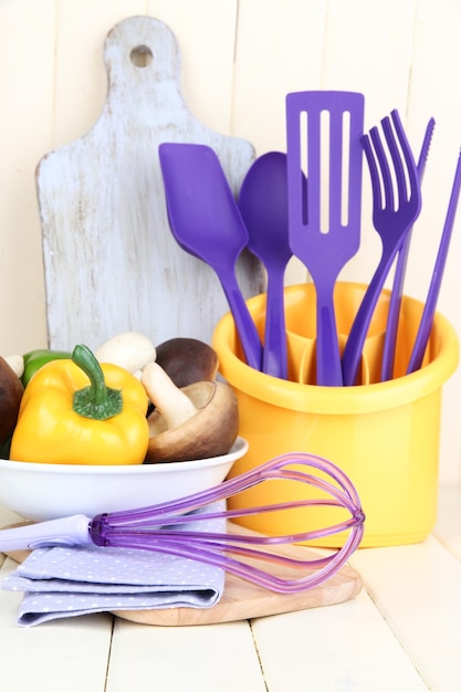 Utensilios de cocina de plástico en taza sobre mesa de madera