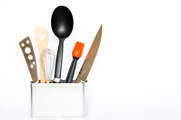 Utensilios de cocina en un recipiente contra un fondo blanco
