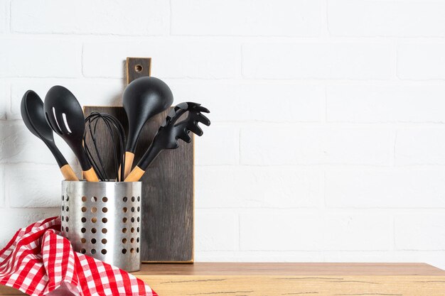 Foto utensilios de cocina con tabla de cortar de madera y toalla cerca de la pared blanca