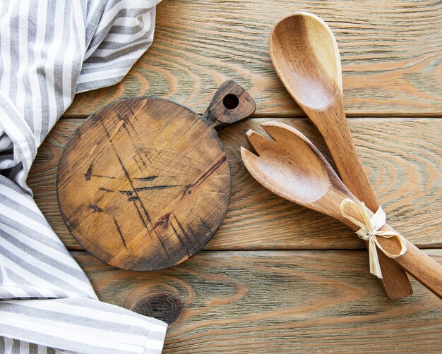 Utensilios de cocina vintage antiguos. Cucharas de madera, tabla de cortar, servilleta. Sobre mesa de madera vieja. Vista superior