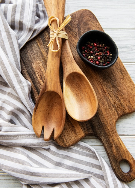 Utensilios de cocina vintage antiguos. Cucharas de madera, tabla de cortar, servilletas y especias sobre mesa de madera blanca. Vista superior