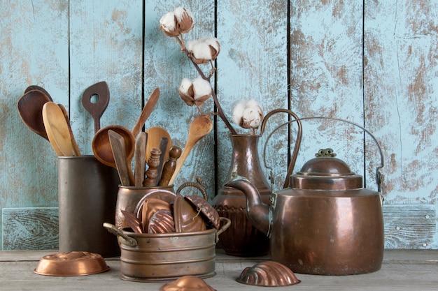 Utensílios de cobre da cozinha do vintage em um fundo azul de madeira.