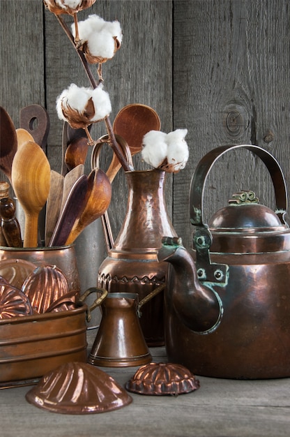 Utensílios de cozinha de cobre vintage em um fundo cinza de madeira.