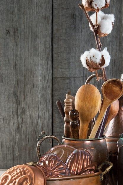 Utensílios de cozinha de cobre vintage em um fundo cinza de madeira.
