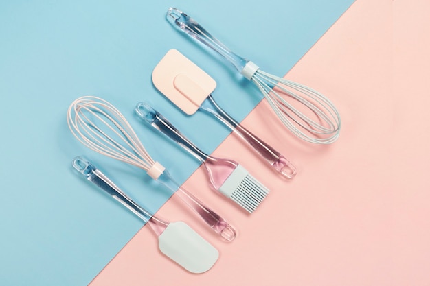 Utensílios de cozinha de silicone azul e rosa ob superfície rosa e azul, vista superior