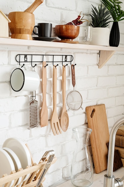 Utensílios de cozinha em cabide de metal preto em cozinha rústica