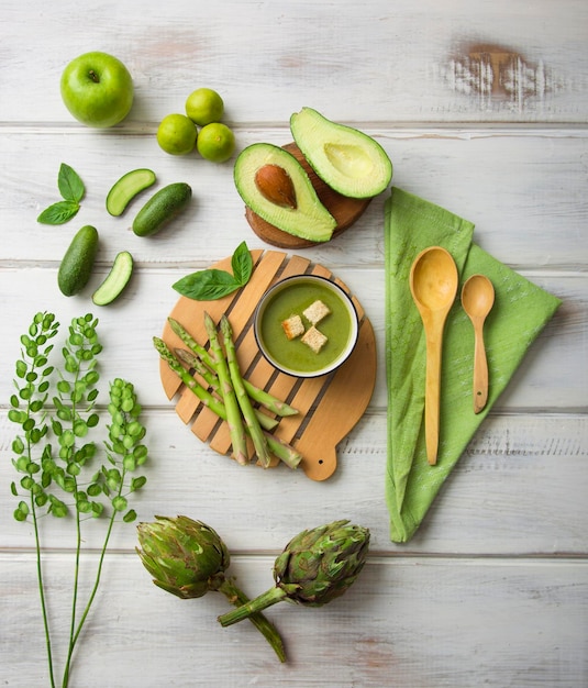 Utensílios de cozinha verde e legumes em alcachofras de abacate de piso de madeira
