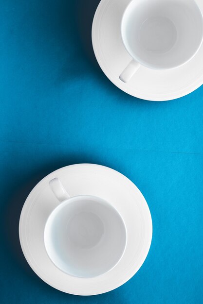 Utensílios de mesa brancos conjunto copo vazio sobre fundo azul flatlay