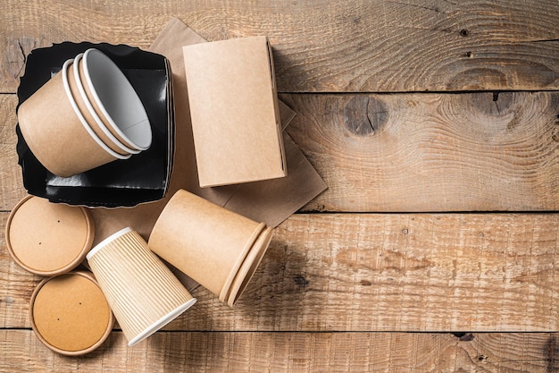 Utensílios de mesa de papel descartáveis Ecologicamente correto Reciclagem conjunto de copos de papel pratos saco recipientes de fast food e talheres Fundo de madeira Vista superior Espaço para cópia