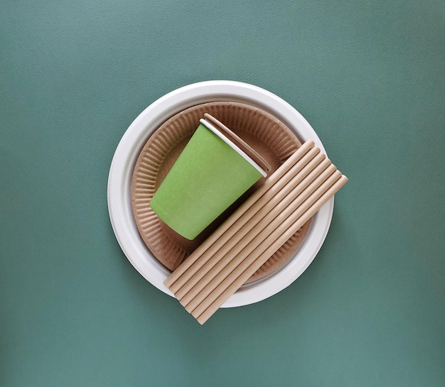 Utensílios de mesa descartáveis ecologicamente corretos na vista superior de fundo verde