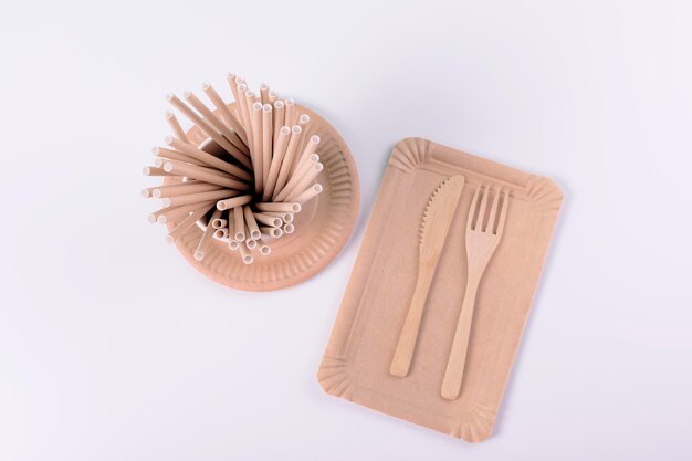 Utensílios de mesa descartáveis ecológicos Pratos de papel copos canudos talheres de madeira em fundo branco Zero desperdício de plástico itens grátis conceito de estilo de vida sustentável plano leigo espaço de cópia