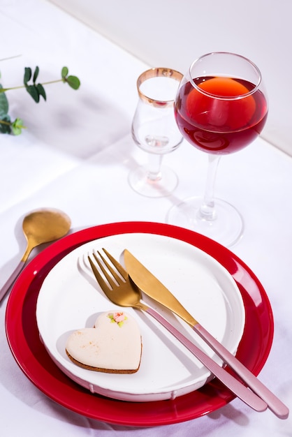 Utensílios de mesa e decorações para servir uma mesa festiva. Pratos, copo de vinho tinto e talheres com folhas verdes