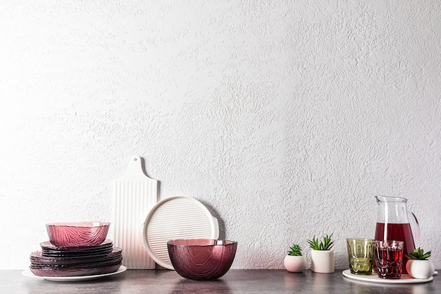 Utensílios de mesa modernos na moda na cor bordô e uma jarra de suco de uva na bancada da cozinha com uma cópia do fundo da cozinha espacial