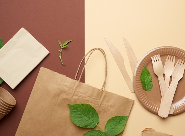 Foto utensílios de papel descartáveis de papel artesanal castanho e materiais reciclados sobre fundo castanho