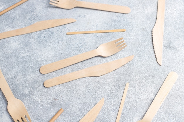 Utensilios desechables ecológicos de madera de bambú y papel sobre un fondo azul. Cucharas drapeadas, tenedor, cuchillos, cuencos de bambú con vasos de papel.