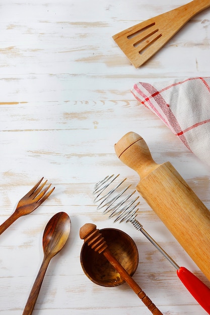 Utensílios para cozinhar e comer em uma mesa de madeira branca