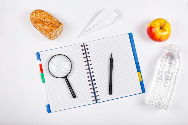 Los útiles escolares y una manzana madura es un símbolo de nuevos conocimientos e ideas sobre el fondo blanco.
