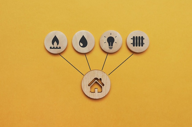 Utility-Symbole auf Holzbechern und einem Haus in der Nähe. Ein Symbol für die notwendigen Dienstleistungen im Haus