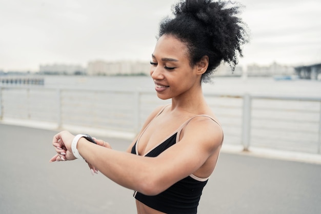 Utiliza un reloj de fitness en el brazo de una joven deportista que entrena en ropa deportiva activa