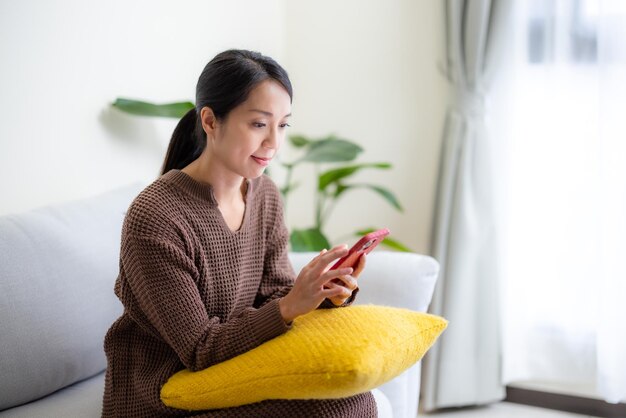 Foto utilización por parte de la mujer del teléfono móvil en el sofá en casa