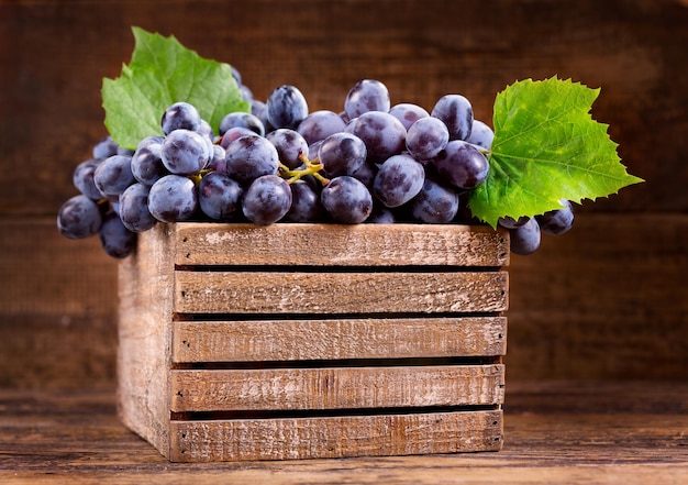 Uva fresca con hojas en una caja de madera