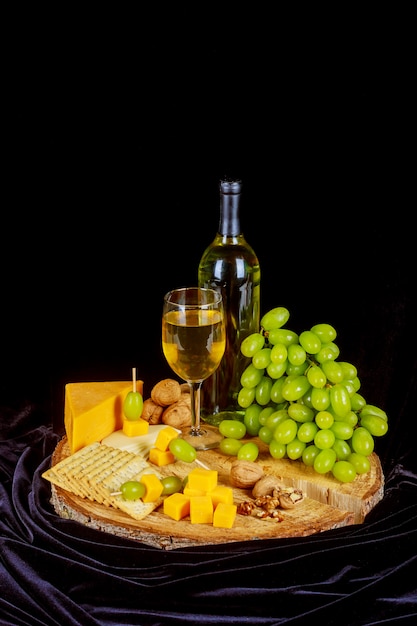 Uva, queso, higos y miel con un vaso de vino blanco sobre un fondo de madera.