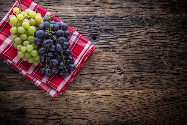 Foto uva. racimo de uvas multicolores sobre mesa de madera rústica.