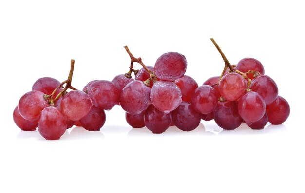 Uva roja madura con gotas aisladas en blanco.